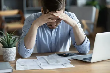 Man stressed looking at bills on his table
