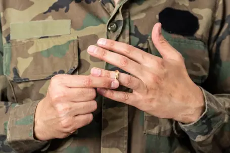 Military man taking off wedding ring
