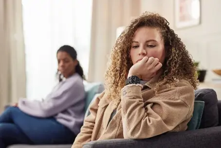 Two women sitting on the couch looking sad