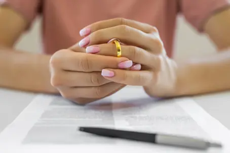 Women taking off wedding ring with documents under her