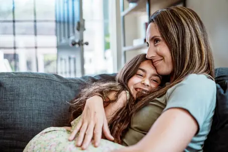 Mom holding daughter on couch
