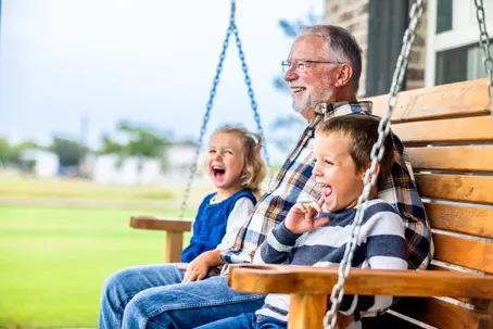 Grandpa sitting on swing with grandchildren