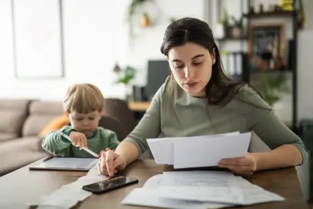 Mother looking at bills with child next to her