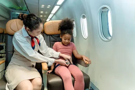 Flight attendant helping young girl on plane