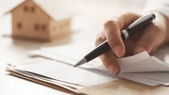 Looking at documents with wooden house blurred in background