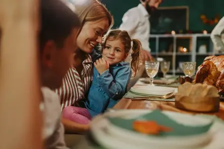 Mother holding daughter during Thanksgiving dinner
