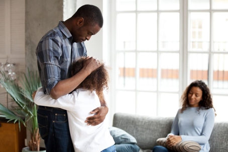 daughter hugging father with mother in background