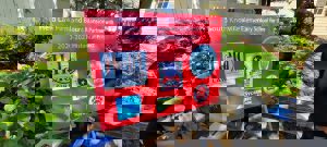 A red outdoor sign, surrounded by green foliage, announces a community partnership. The sign reads: "Held Law Firm and Blaun Mansion Partner with South Knoxville Elementary School for the 2020-2021 Historical Project."