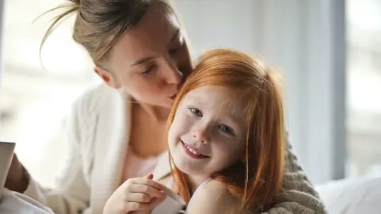 Mother kisses her daughter, who looks happy to see her